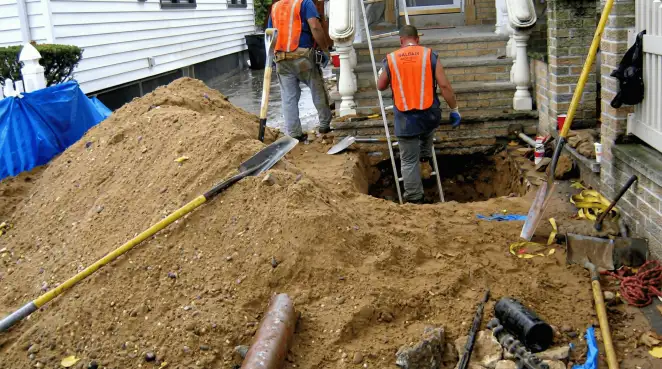 Contractors performing foundation protection and exterior drainage excavation near residential home steps in Anchorage, AK